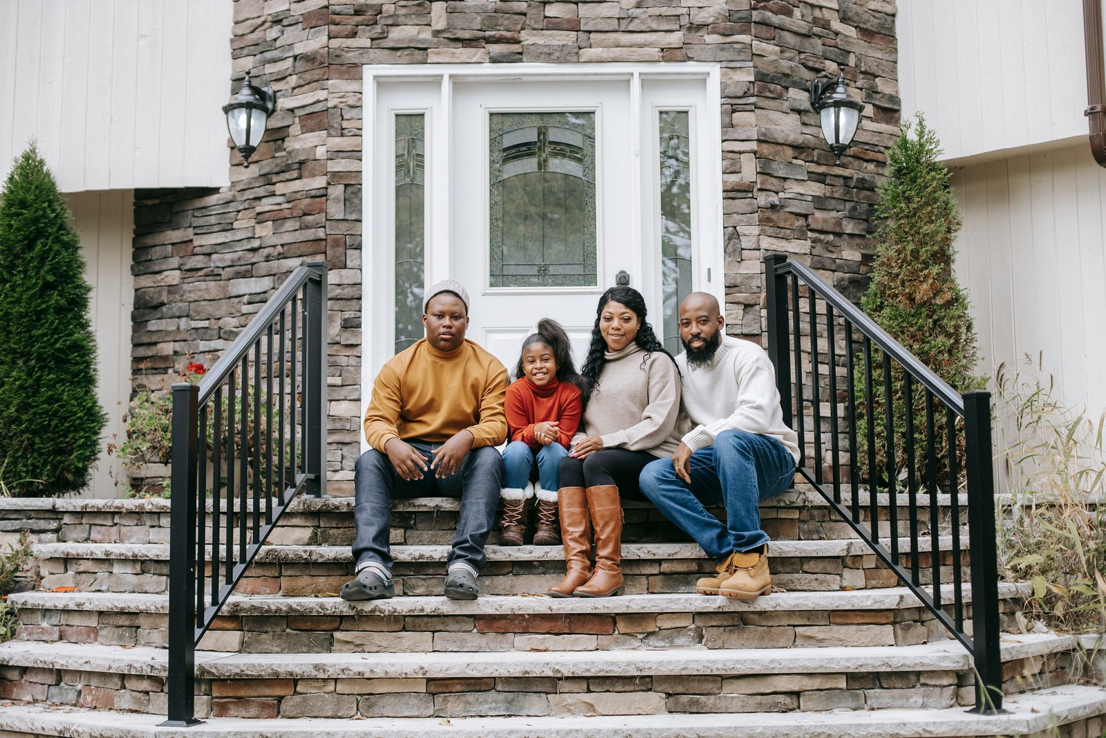 Young family sitting on the steps of their first home